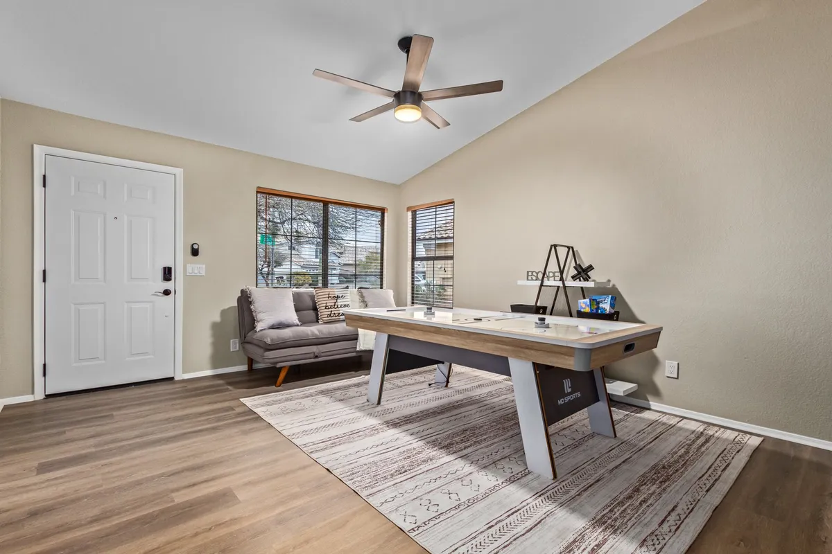 A bright and inviting living space with a comfortable sofa, stylish coffee table, and a well-placed ceiling fan above. Sunlight streams in, highlighting the welcoming mood and practical features designed for year-round comfort. The decor is contemporary yet inviting, and the ceiling fan is a clear nod to the described amenities.